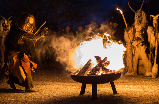 Perchten tanzen um ein Feuer